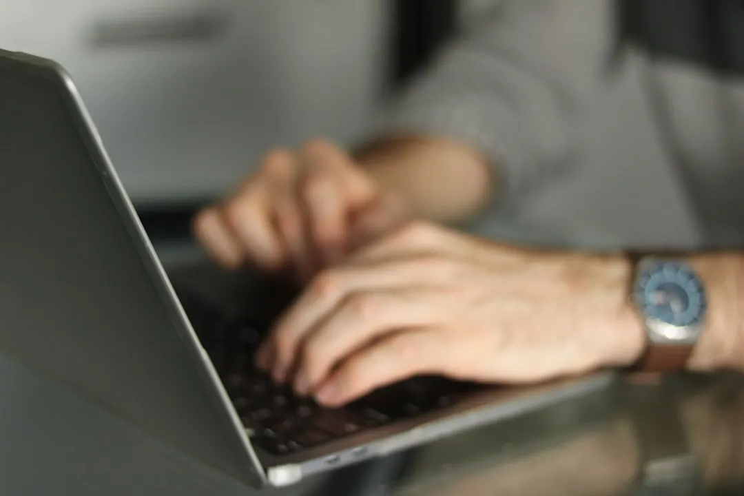 ノートパソコンのキーボードに置かれた両手